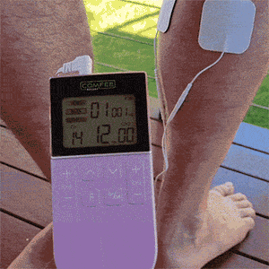 TENS Comfee power3 is on and displaying some settings. The TENS machine is purple and is photograhed in front of a set of legs. You can see the electrode pads sitting on the right calf of a man. The Comfee Relief logo is displayed on the top of the TENS machine. 